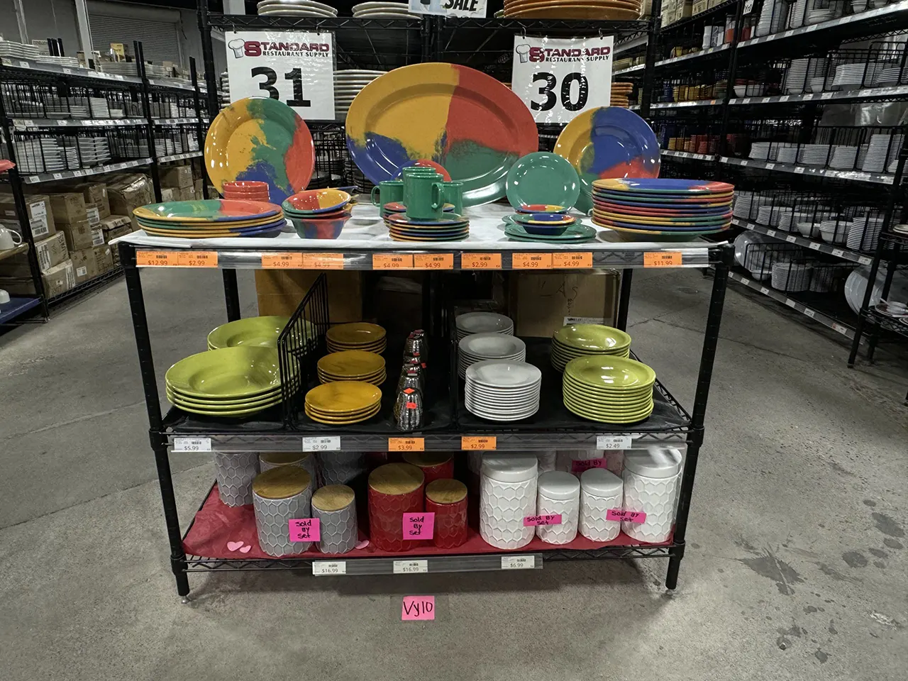 Colorful dinnerware display at Standard Restaurant Supply, featuring plates, bowls, and mugs in vibrant hues, showcasing diverse kitchenware options for culinary enthusiasts.