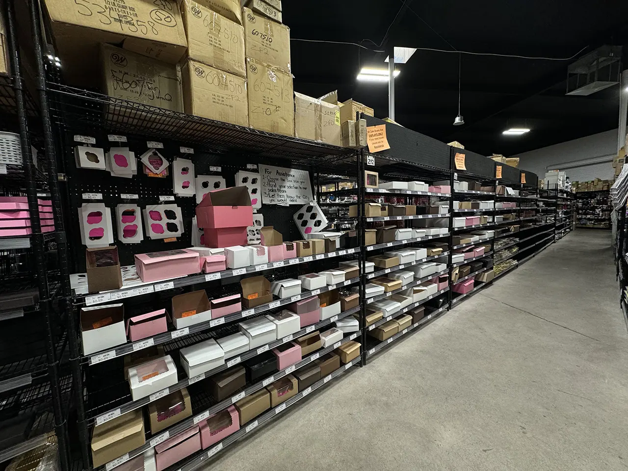 Aisle of diverse packaging and baking supplies, featuring various boxes in pink, brown, and white, showcasing the extensive inventory at Standard Restaurant Supply in Las Vegas.
